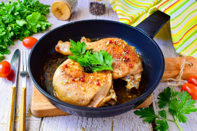 Fried chicken legs in a pan with garlic