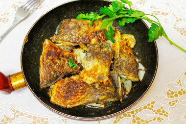 Fried crucian carp in a frying pan in flour