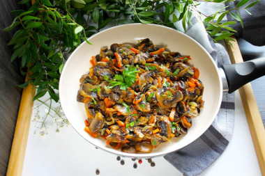 Fried mushrooms with onions and carrots in a frying pan