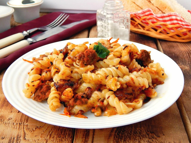 Chicken hearts with pasta on frying pan