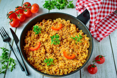 Rice with minced meat and tomato paste in a frying pan