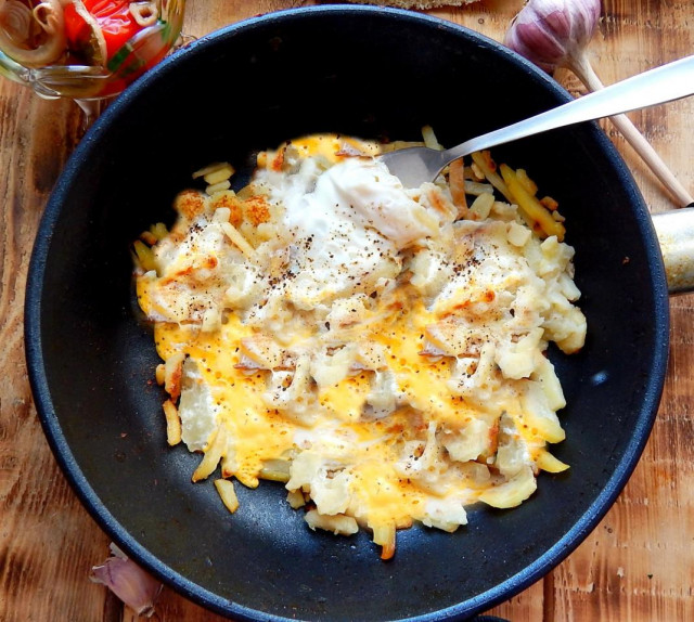 Fried potatoes with egg in a frying pan