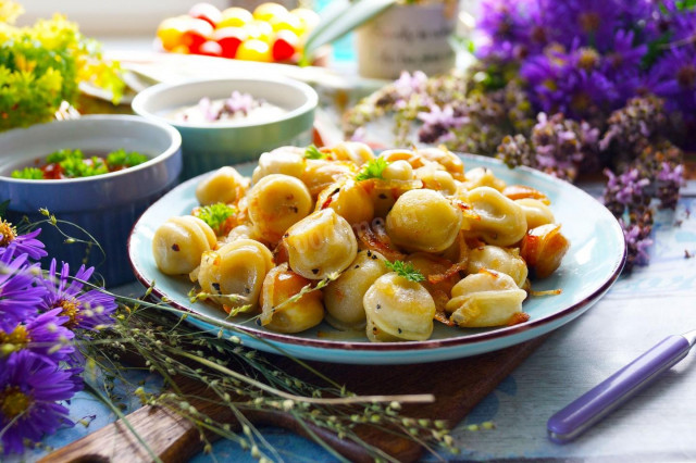 Fried dumplings with onions in a frying pan