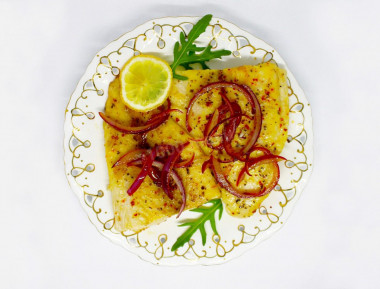 Pangasius in a frying pan with fried onion