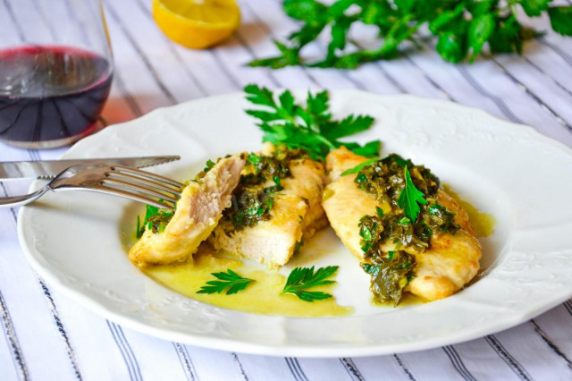 Fried chicken fillet in a pan with lemon and herbs