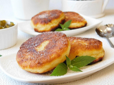 Fluffy cottage cheese pancakes with flour in a frying pan