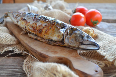 Grilled mackerel on a grill on coals in foil baked