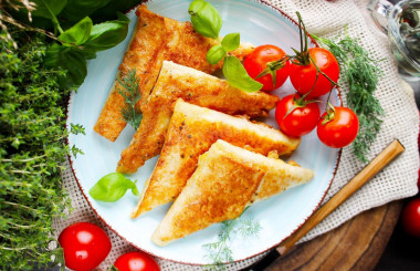 Triangles of pita bread with ham and cheese in a frying pan