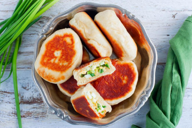 Pies with egg and green onions in a frying pan