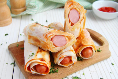 Sausages in pita bread in a frying pan with cheese