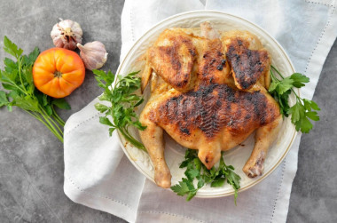 Tobacco chicken in a frying pan under a classic press