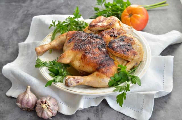 Tobacco chicken in a frying pan under a classic press