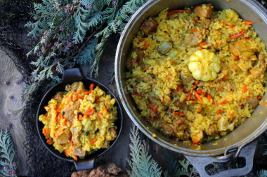 Pork pilaf in a cauldron over a campfire