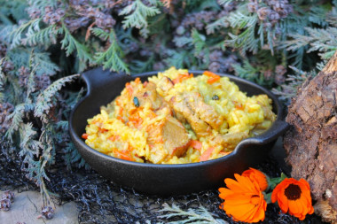 Pork pilaf in a cauldron over a campfire