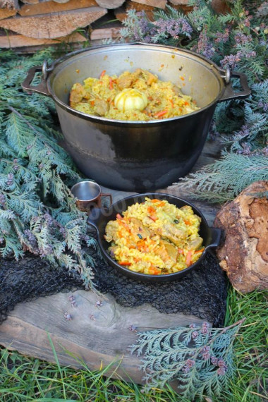 Pork pilaf in a cauldron over a campfire