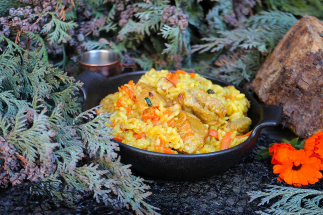 Pork pilaf in a cauldron over a campfire